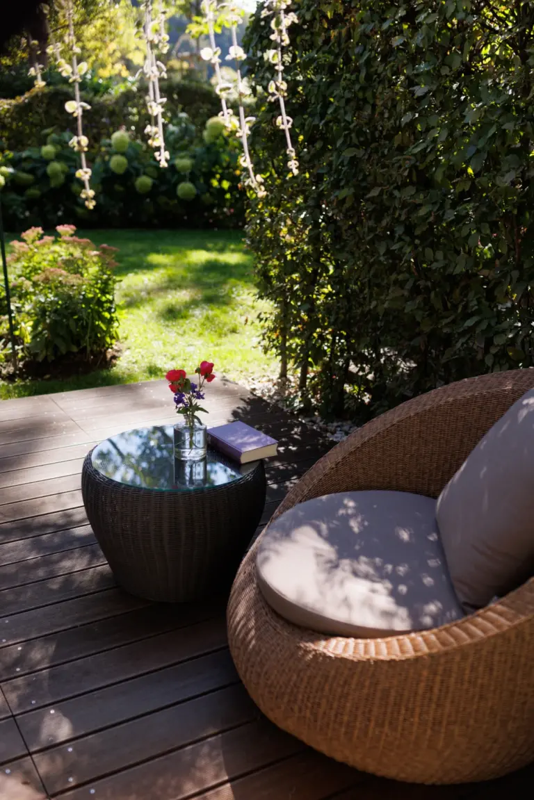Bild zeigt einen modernen Gartensessel und einen kleinen Tisch in einer ruhigen, üppig begrünten Gartenterrasse des Hotels Weinlandhof Gamlitz in der Südsteiermark